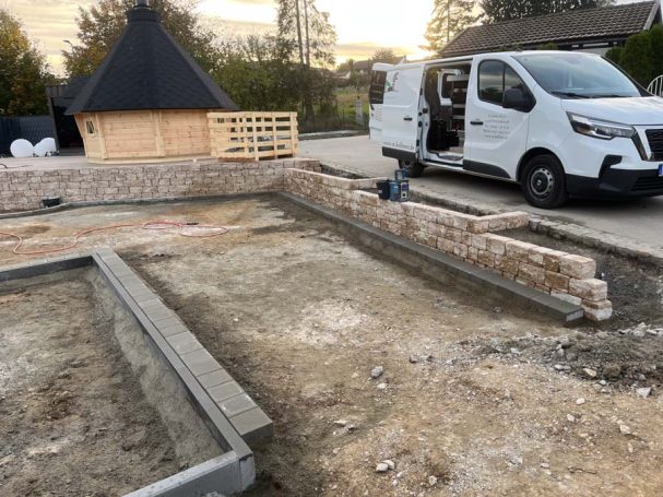 Baustelle mit unvollständigem Fundament und Lieferwagen im Hintergrund.