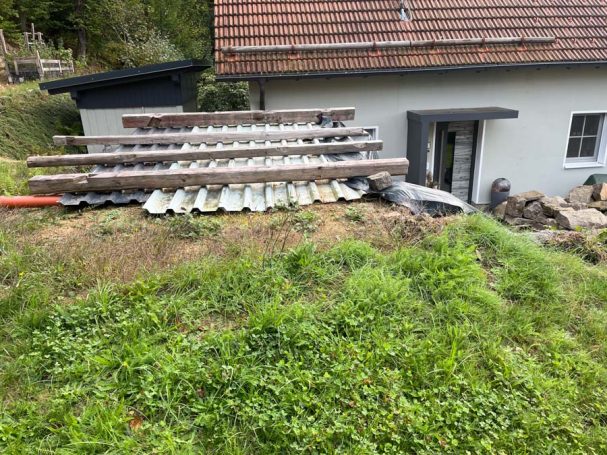 Hintergrund mit einer kleinen Baustelle, Holzplanken und einem Gebäudeeingang.
