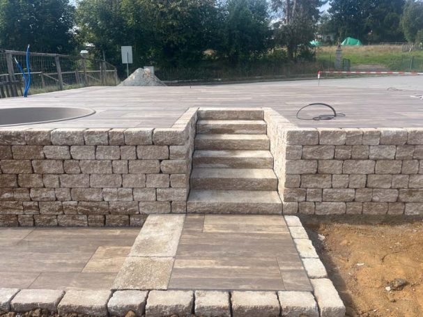 Gestufte Treppe aus Steinen auf einer gepflasterten Fläche in einem Außenbereich.