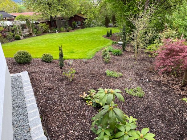 Blick auf einen gepflegten Garten mit Rasen und bunten Pflanzen.