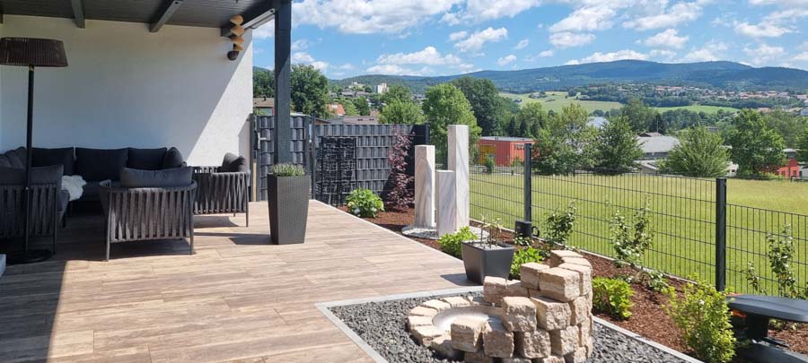 Terrasse mit gemütlicher Sitzgelegenheit und Blick auf eine grüne Landschaft.