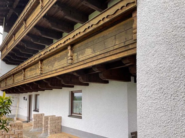 Holzrückseite eines Gebäudes mit einem Balkon und verzierten Holzpaneelen.